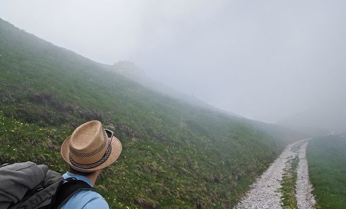 Scenic view of mountains with man standing on road against sky