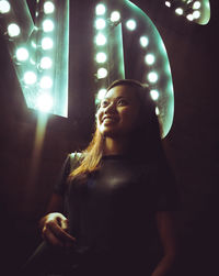 Young woman standing in illuminated room