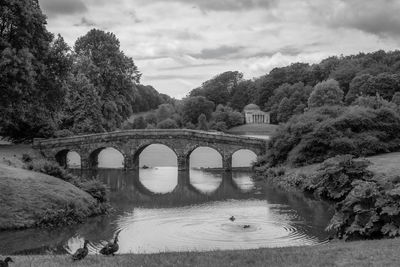 Arch bridge over river against sky