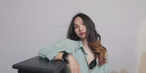 Portrait of beautiful young woman standing against wall