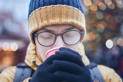 Close-up of man drinking coffee while wearing hat