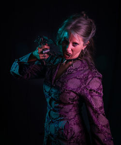 Portrait of spooky woman standing against black background