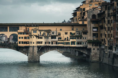 Arch bridge over river against buildings in city