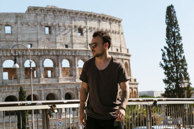 Young man wearing sunglasses while standing against coliseum