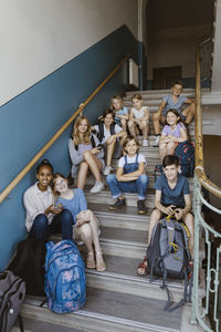 Portrait of smiling multiracial male and female students sitting on school staircase