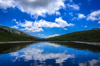 Scenic view of lake and mountains against blue sky