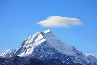 Low angle view of snowcapped mountain against blue sky