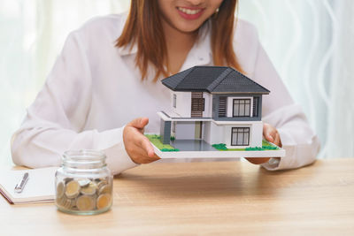 Midsection of woman holding umbrella while sitting on table in house