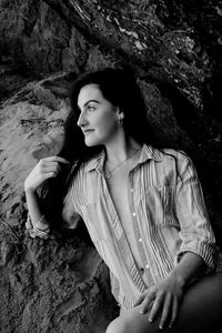 Young woman looking away while sitting on rock