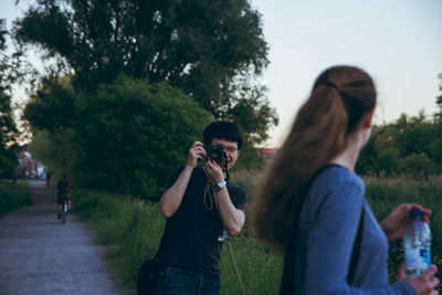 Rear view of woman photographing through smart phone against sky