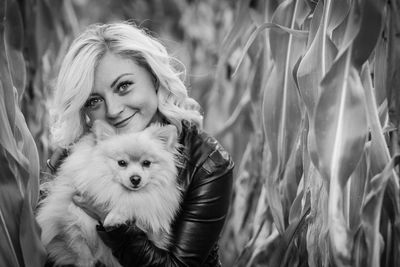 Portrait of young woman with dog by plants