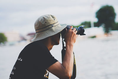 Portrait of man photographing against sky