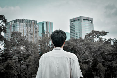 Rear view of man against buildings in city