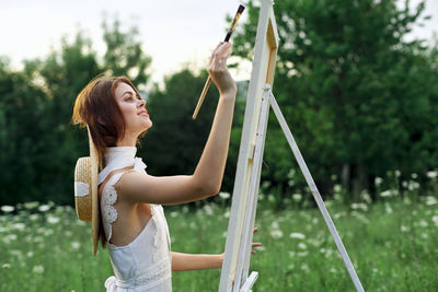 Young woman standing by tree against plants