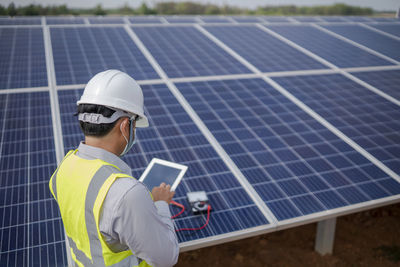 Rear view of man working on solar panel