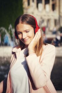 Smiling woman listening music in city