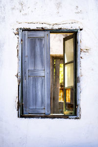 Antique window on a white old wall and gold light inside.