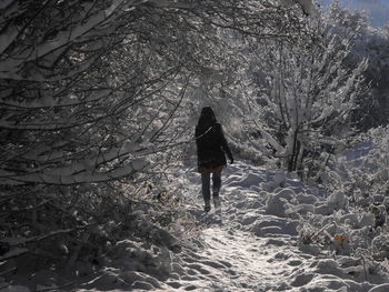 Rear view of woman walking on snow covered land