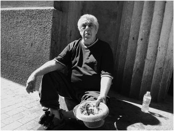 PORTRAIT OF MAN SITTING WITH ICE CREAM OUTDOORS