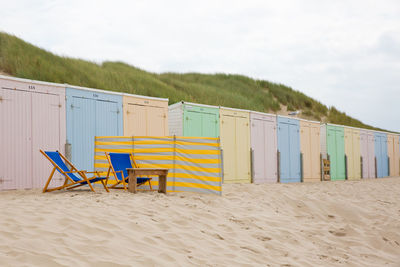 Hooded chairs on beach against sky