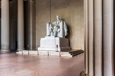 Statue in front of wooden column