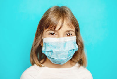 Portrait of girl wearing protective face mask against blue background