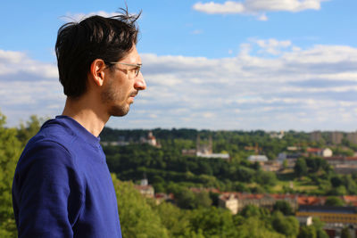 Man looking away while standing against sky