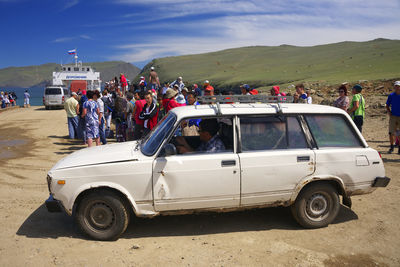 People on road by mountain against sky