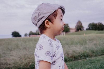 Cute boy sticking out tongue while standing on land