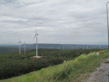 Wind turbines on field against sky