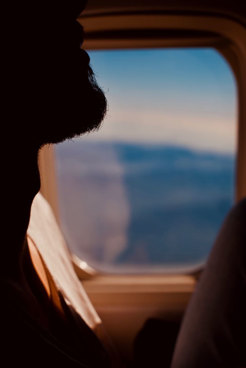 MAN LOOKING THROUGH WINDOW AT SUNSET