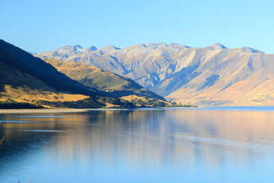 Scenic view of lake and mountains against blue sky