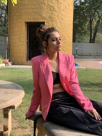 Young woman looking away while sitting outdoors