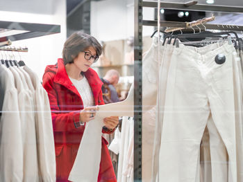 Woman chooses trousers at clothing store. casual trousers on hangers. shop window. shopping at mall.