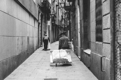 Rear view of people walking on street amidst buildings