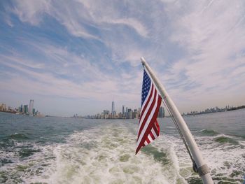 Flag on building by sea against sky