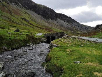 Scenic view of stream amidst mountains against sky