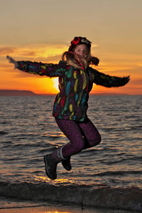 A young girl jumps for joy in front of the setting sun at wasaga beach provincial park. 