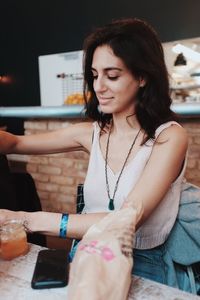 Close-up of young woman using mobile phone while sitting on table