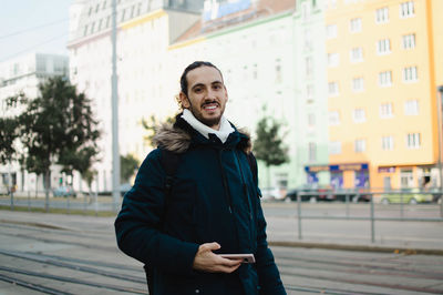 Smiling guy with long hair traveling in europe during winter time - vienna, austria