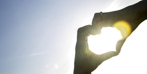 Midsection of man holding sun against sky