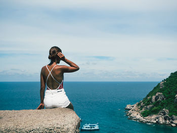 Rear view of woman looking at sea against cloudy sky