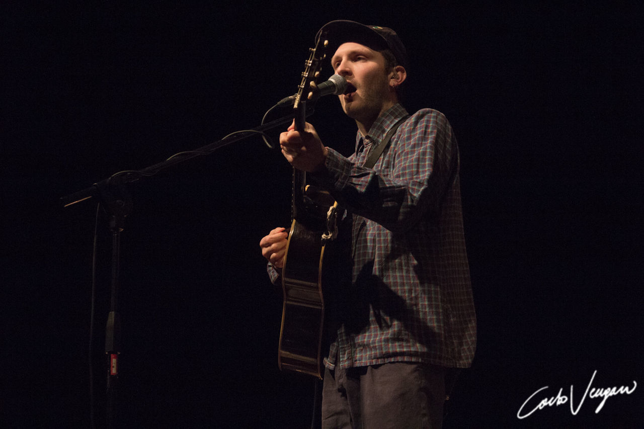 performance, music, arts culture and entertainment, input device, microphone, holding, one person, singing, musician, singer, young men, real people, young adult, three quarter length, indoors, lifestyles, musical instrument, men, performing arts event, black background, stage, skill, microphone stand, plucking an instrument