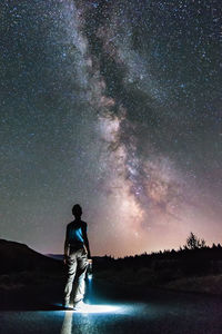 Rear view of man standing against star field at night