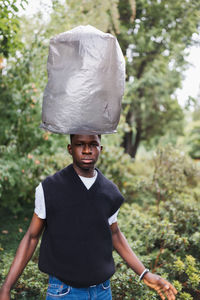 Young african man with plastic over head. plastic pollution concept