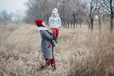 Mother and little baby daughter walking together and having fun in autumn nature background.