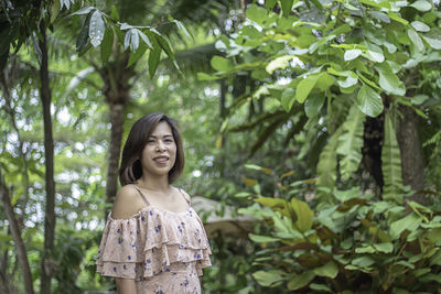 Portrait of smiling young woman against trees in forest