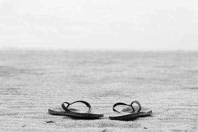 Slippers on beach against sky