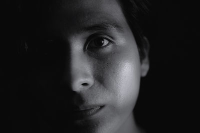 Close-up portrait of young man against black background