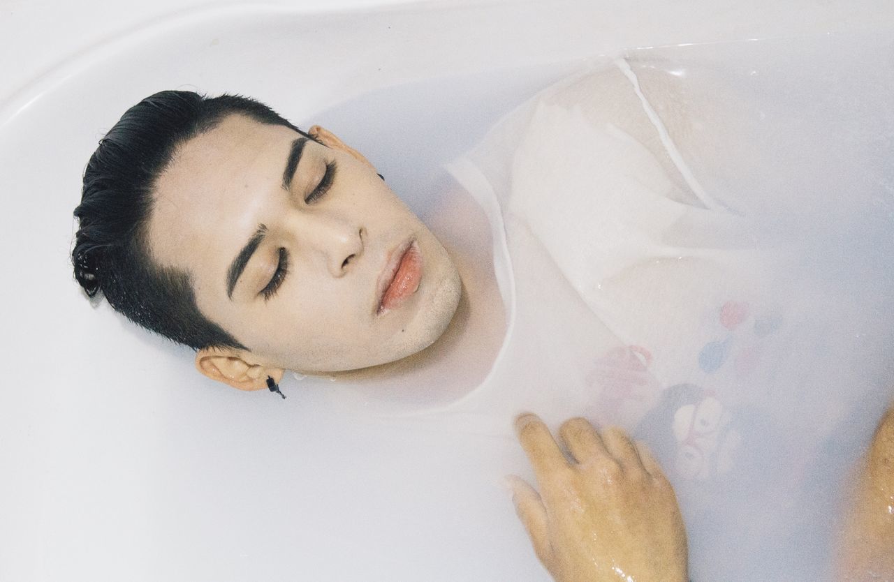 HIGH ANGLE VIEW OF YOUNG WOMAN LYING DOWN ON HAND